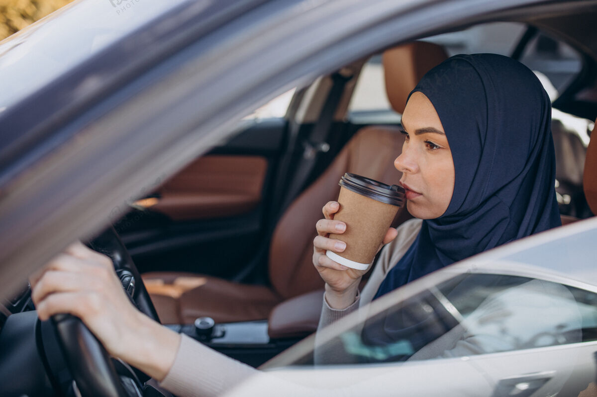 车辆年轻的现代穆斯林妇女在车里喝咖啡种族表情宗教