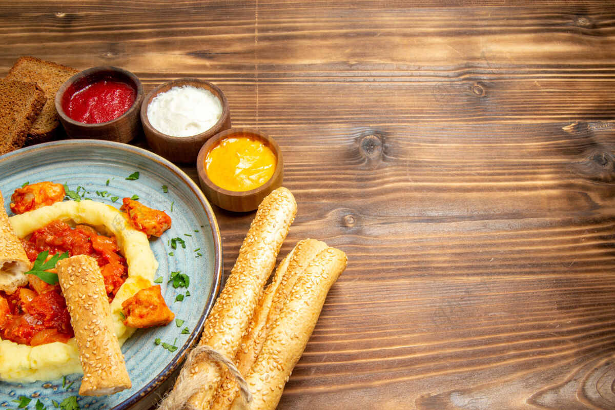 食物正面图美味的鸡肉片 土豆泥和面包放在木桌上 土豆饭 辣椒胡椒玉米晚餐