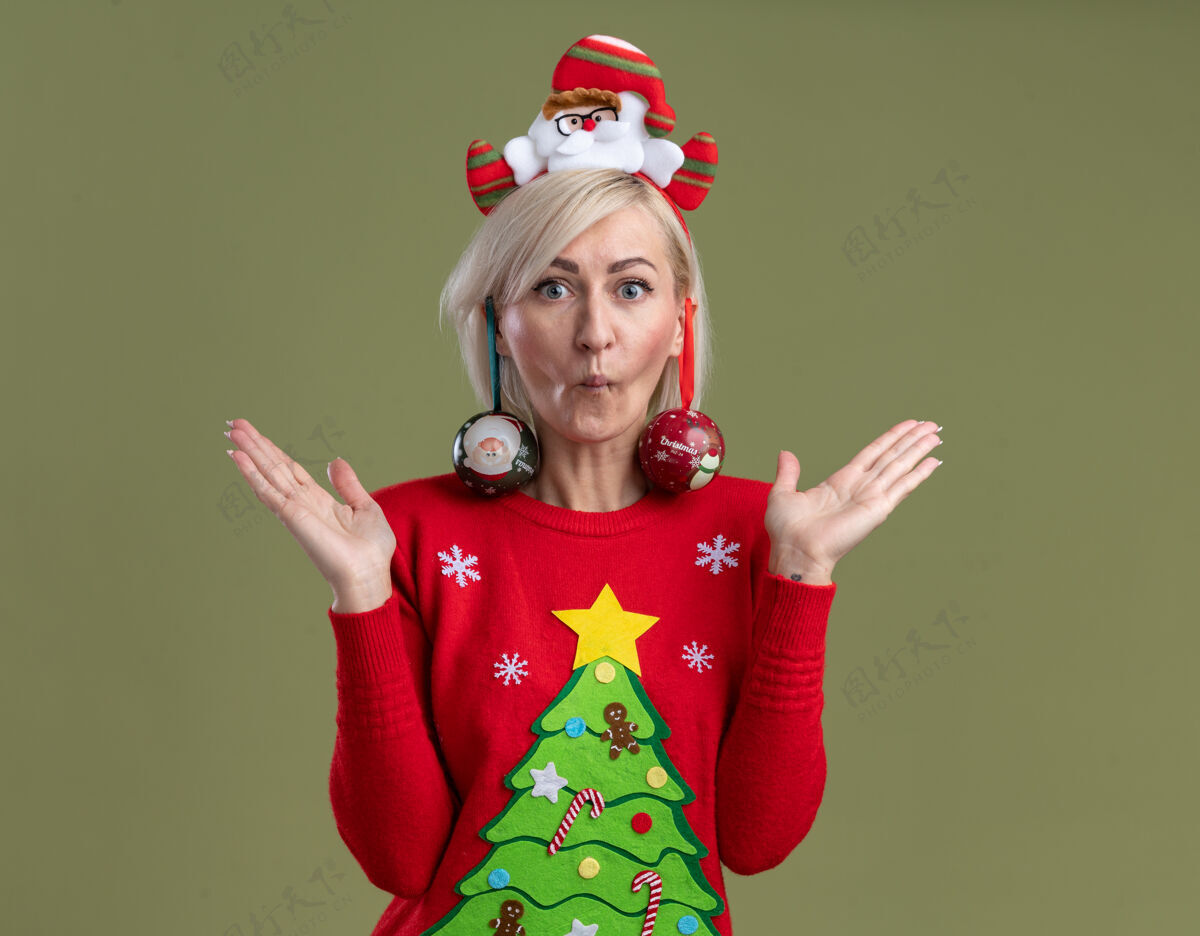 挂愚蠢的中年金发女人 戴着圣诞老人的头带 穿着圣诞毛衣 撅着嘴唇 两手空空的 耳朵上挂着圣诞饰品 孤零零的挂在橄榄绿的墙上金发女人圣诞老人