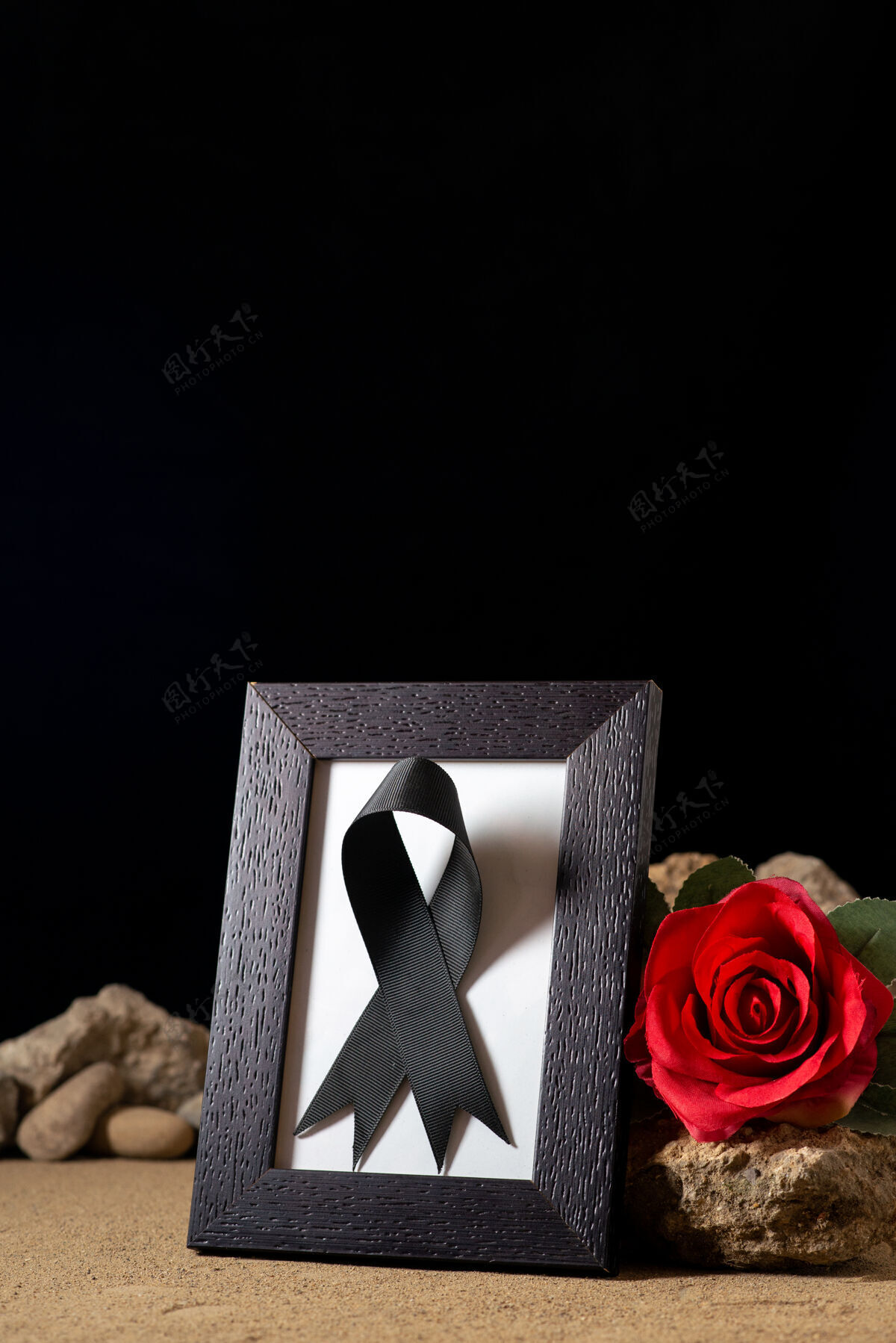 死亡带红色花朵和黑色石头的空相框的正面视图红色葬礼玫瑰