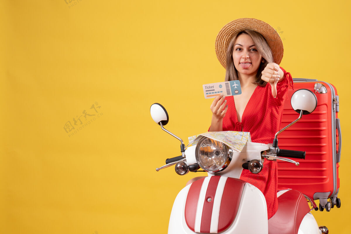 冒险正面图：穿着红裙子的年轻女士拿着车票在轻便摩托车上竖起大拇指漂亮度假行李