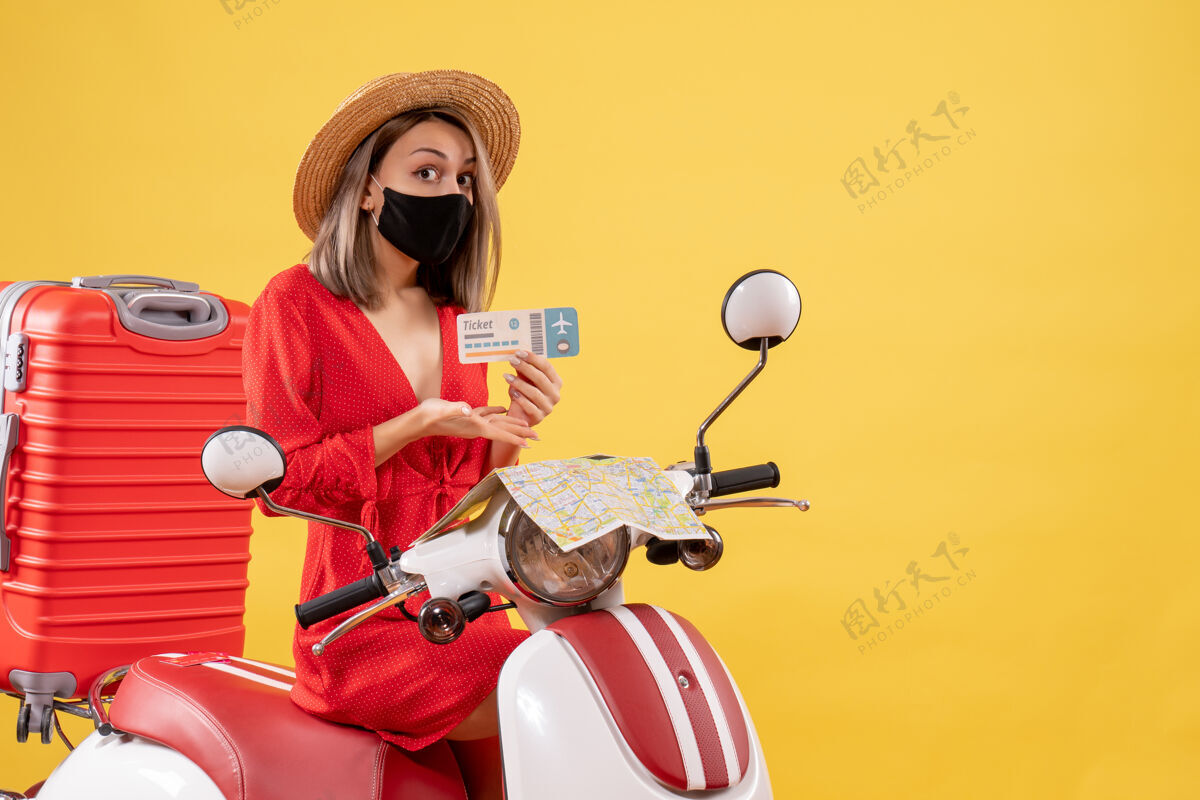 流行病前视图：骑着轻便摩托车的年轻女士 红色手提箱指着车票肖像旅游新常态