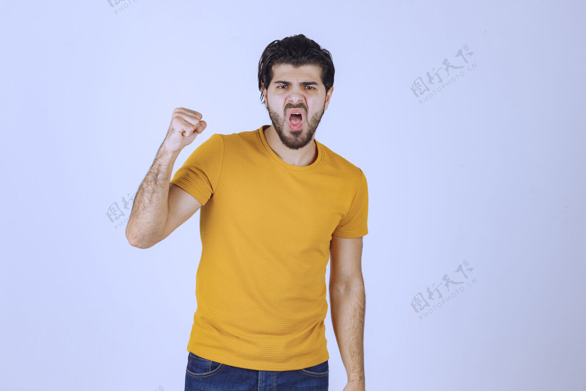 年轻人穿黄衬衫的男人展示他的拳头和力量姿势人类人