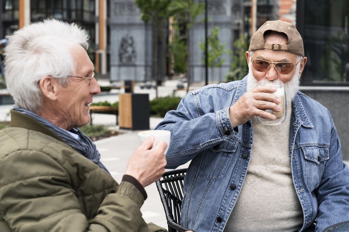 户外城里两个老男人一起喝咖啡聊天老年人咖啡城市