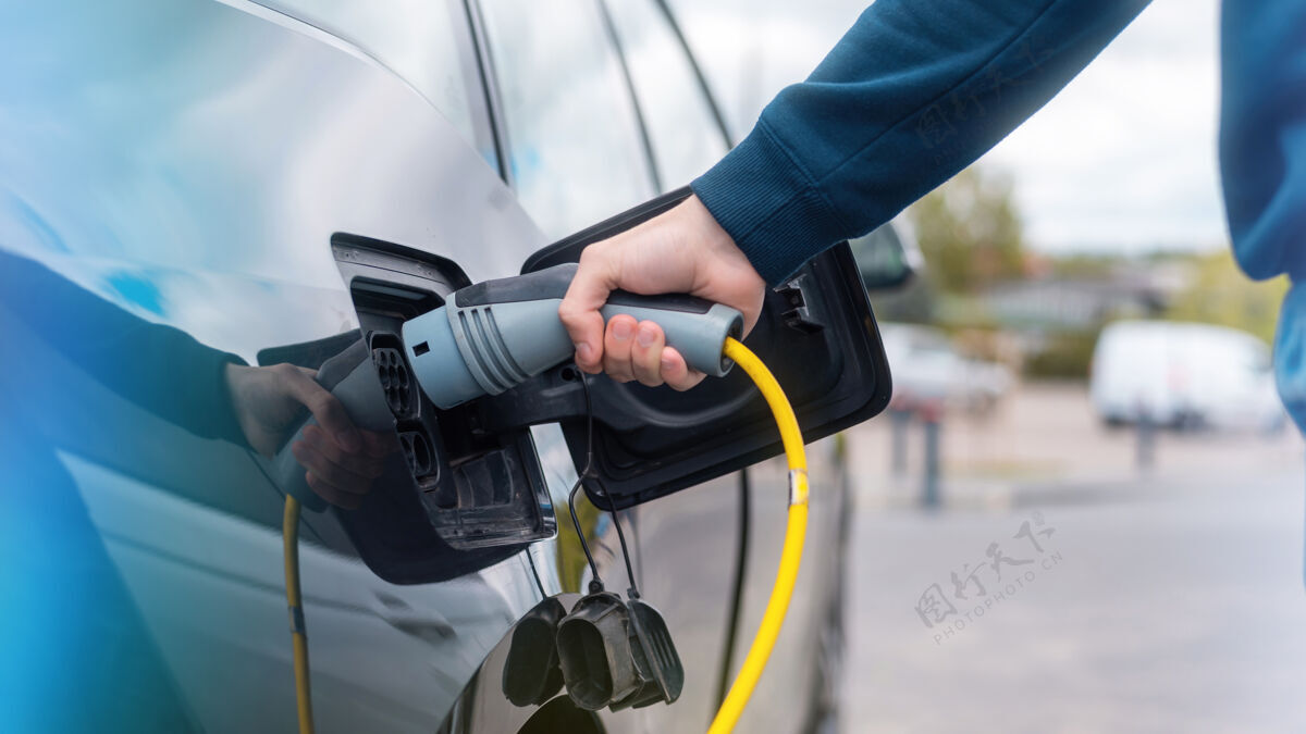 驾驶在充电站把充电器插进电动车的人环境加油绿色