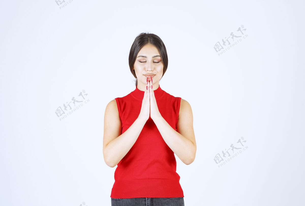 精神穿红衬衫的女孩双手合十祈祷冥想模特休闲