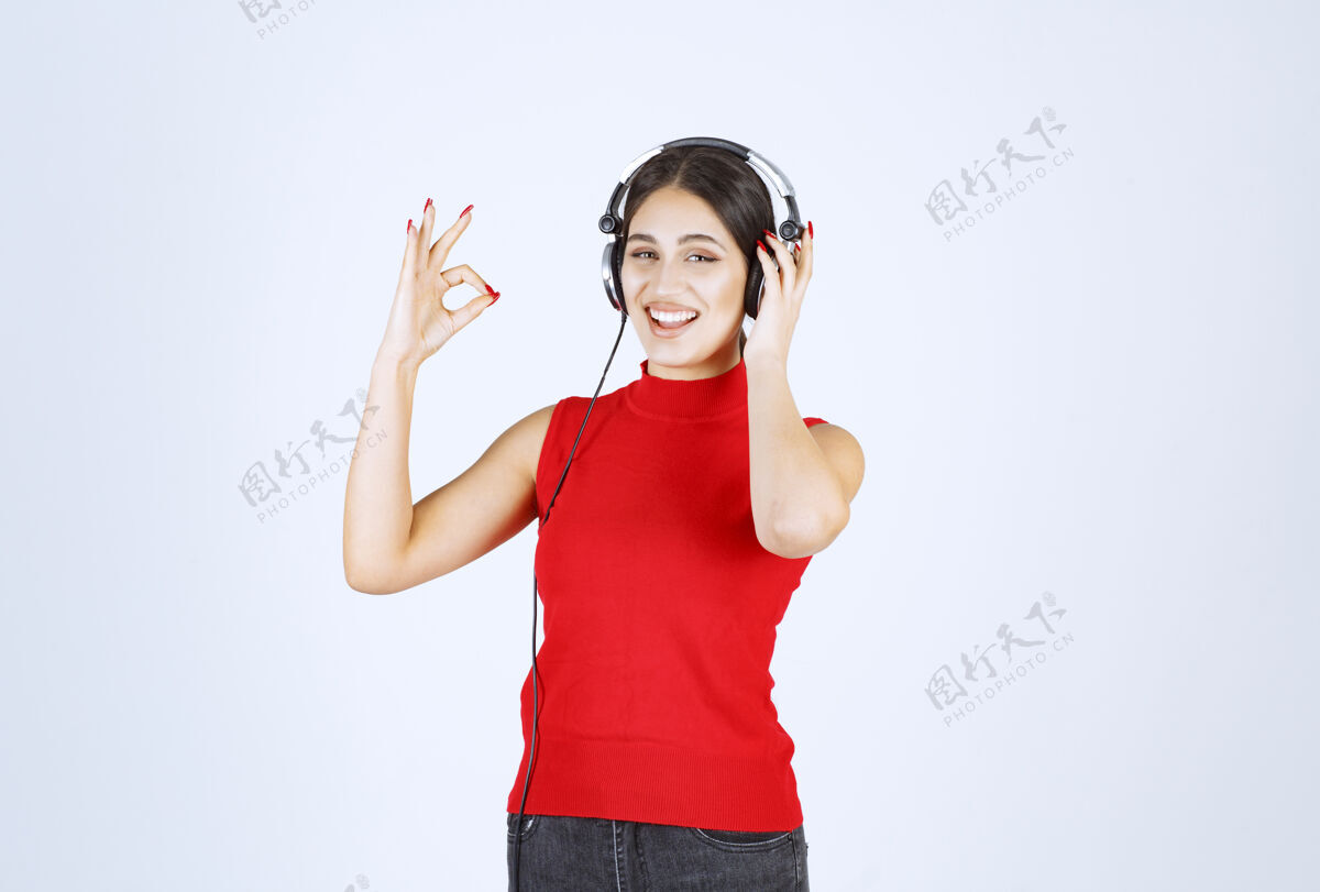 人类穿着红衬衫的Dj戴着耳机欣赏音乐女人年轻表演