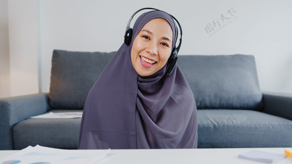社交亚洲穆斯林女士戴着耳机用笔记本电脑在客厅远程工作时 在视频电话会议上和同事谈论计划会议年轻人网络