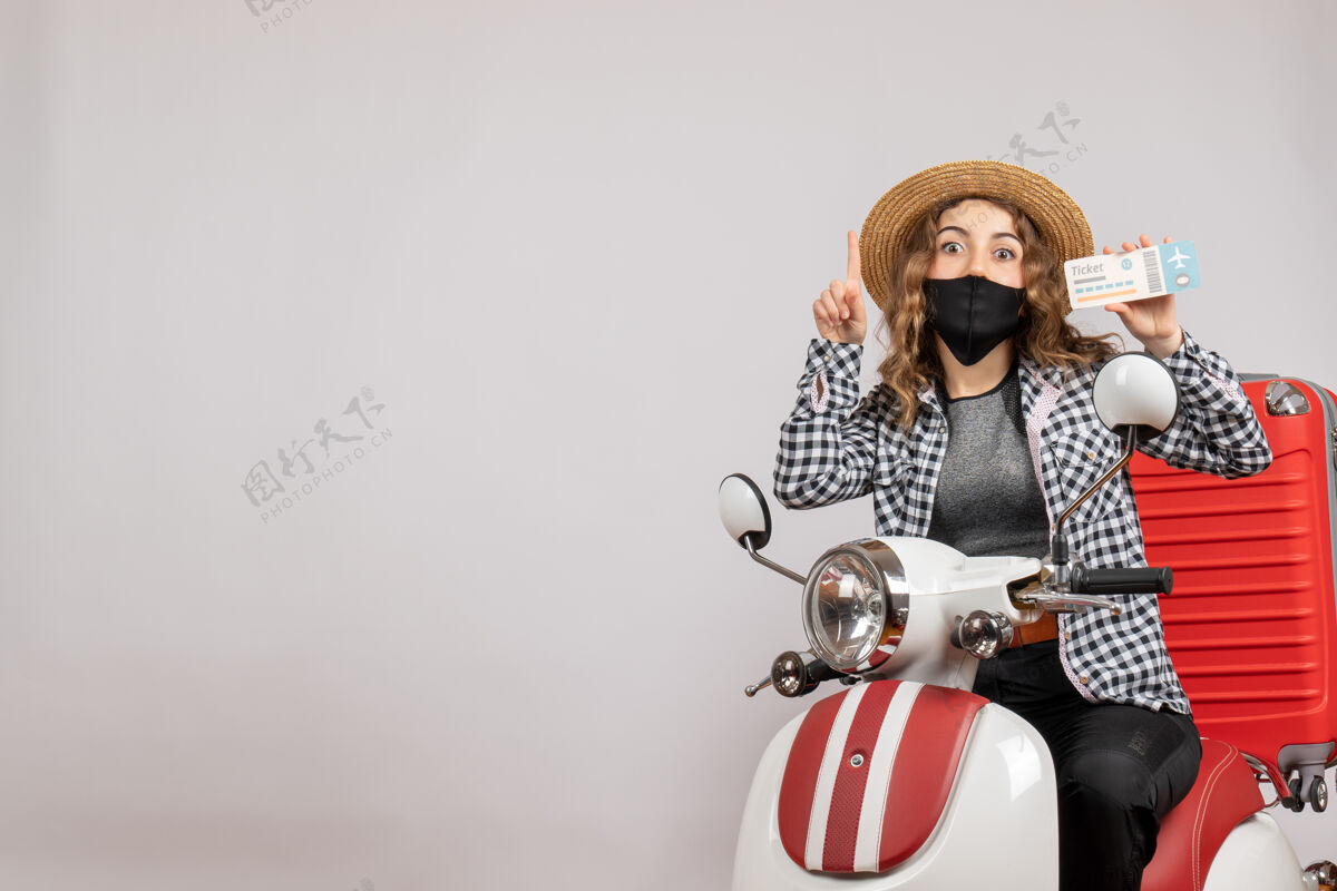滑板车正面图：坐在轻便摩托车上的年轻女孩提着手提箱拿着票轻便摩托车旅行者旅行