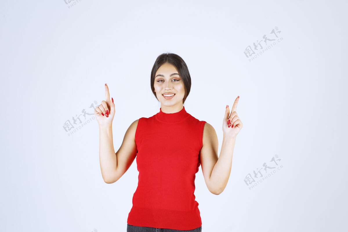 年轻穿红衬衫的女孩举手指着上面职员工人女