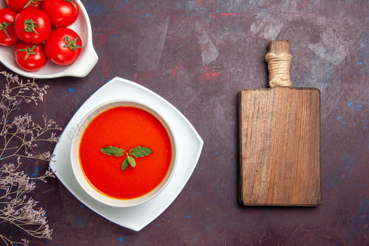 视图俯瞰美味的西红柿汤配上新鲜西红柿的深色背景菜酱汁西红柿色一餐汤新鲜午餐容器