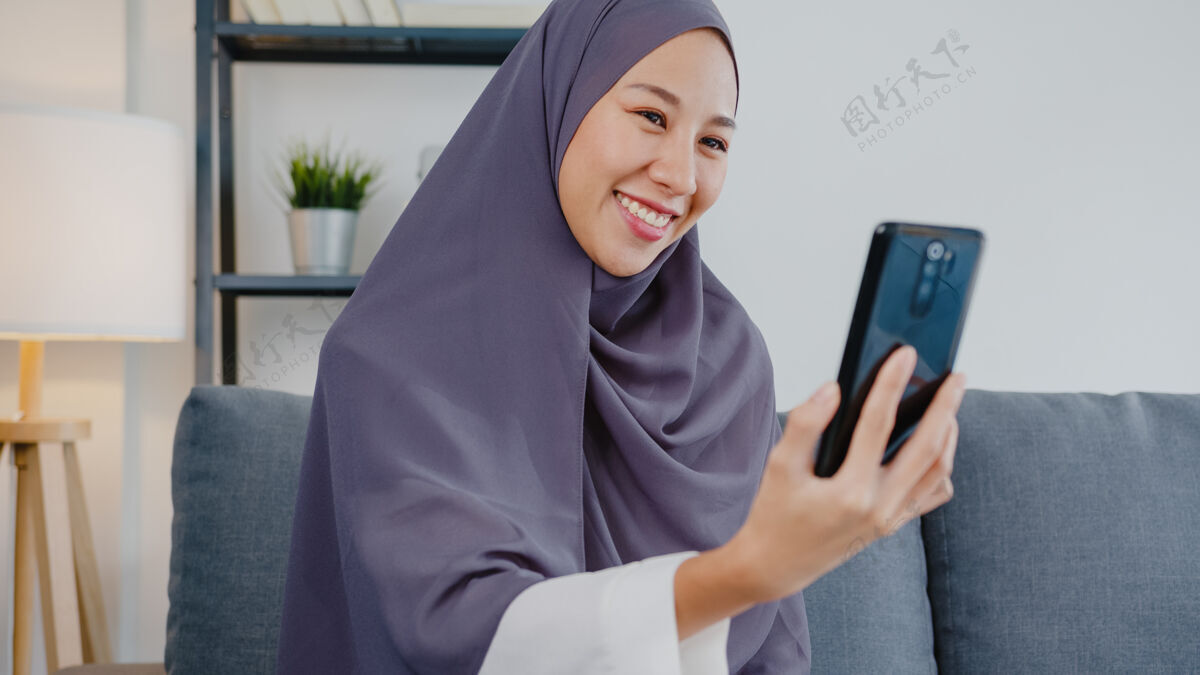 媒体穆斯林女士戴着头巾 在家里用电话视频通话和夫妇交谈手机电话个人
