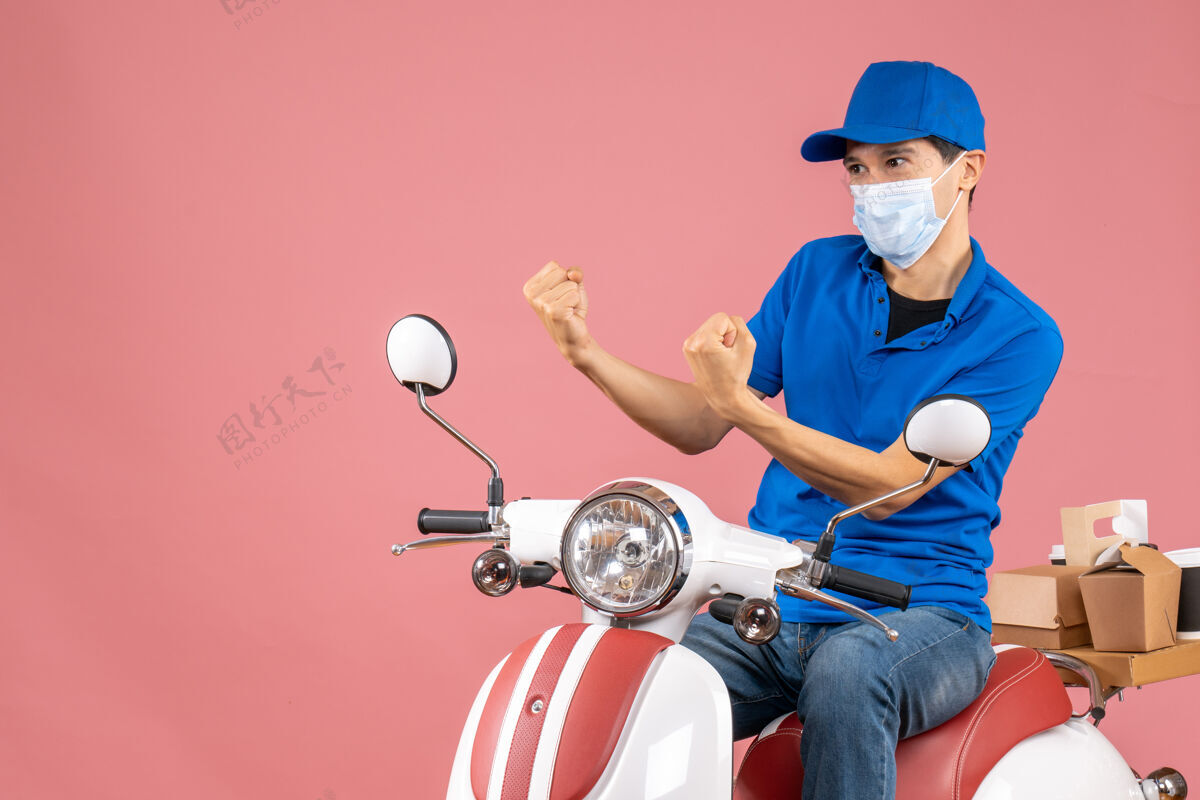 车辆俯视图紧张的快递员戴着医用面罩戴着帽子坐在粉彩桃色背景的踏板车上滑板车背景紧张