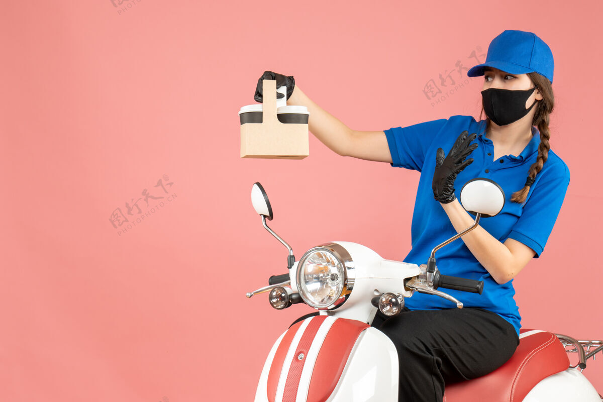 剪影前视图的希望女性送货人戴着医用口罩和手套坐在滑板车上传递粉彩桃背景的命令交付穿滑板车