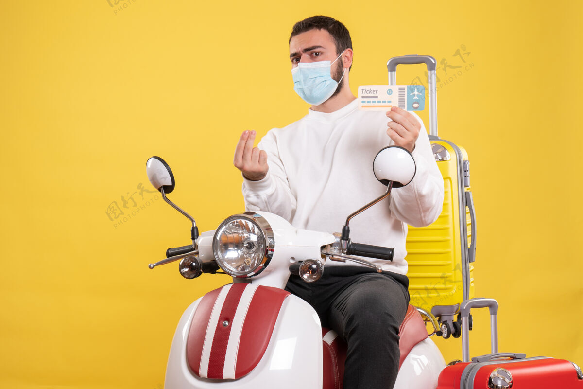 旅行旅行概念的俯视图 年轻好奇的家伙戴着医用面罩坐在摩托车上 黄色手提箱放在上面 手里拿着车票成人男面具