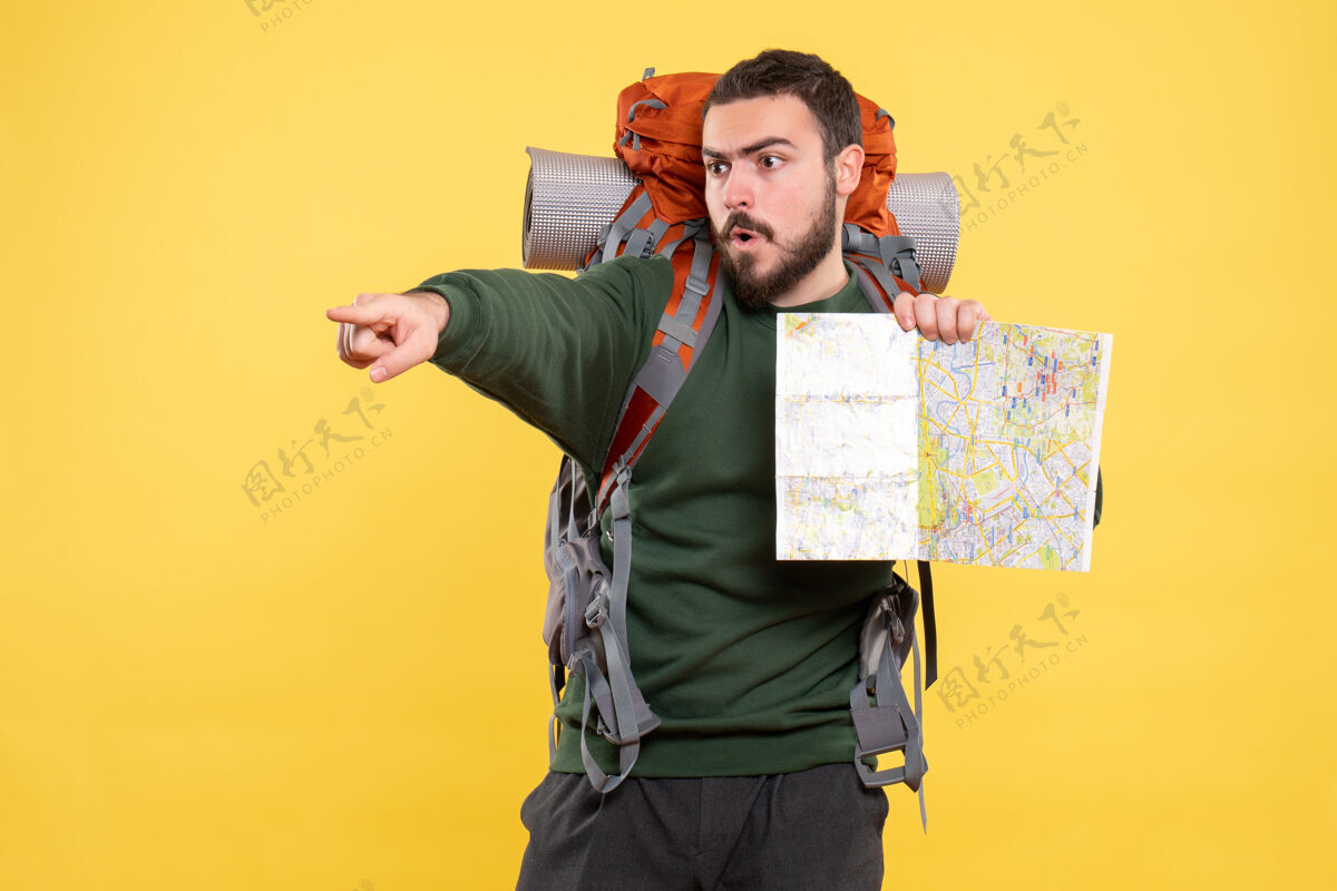 商务顶视图年轻的愤怒旅行的家伙背着背包拿着地图 指着黄色的前方专业年轻肖像