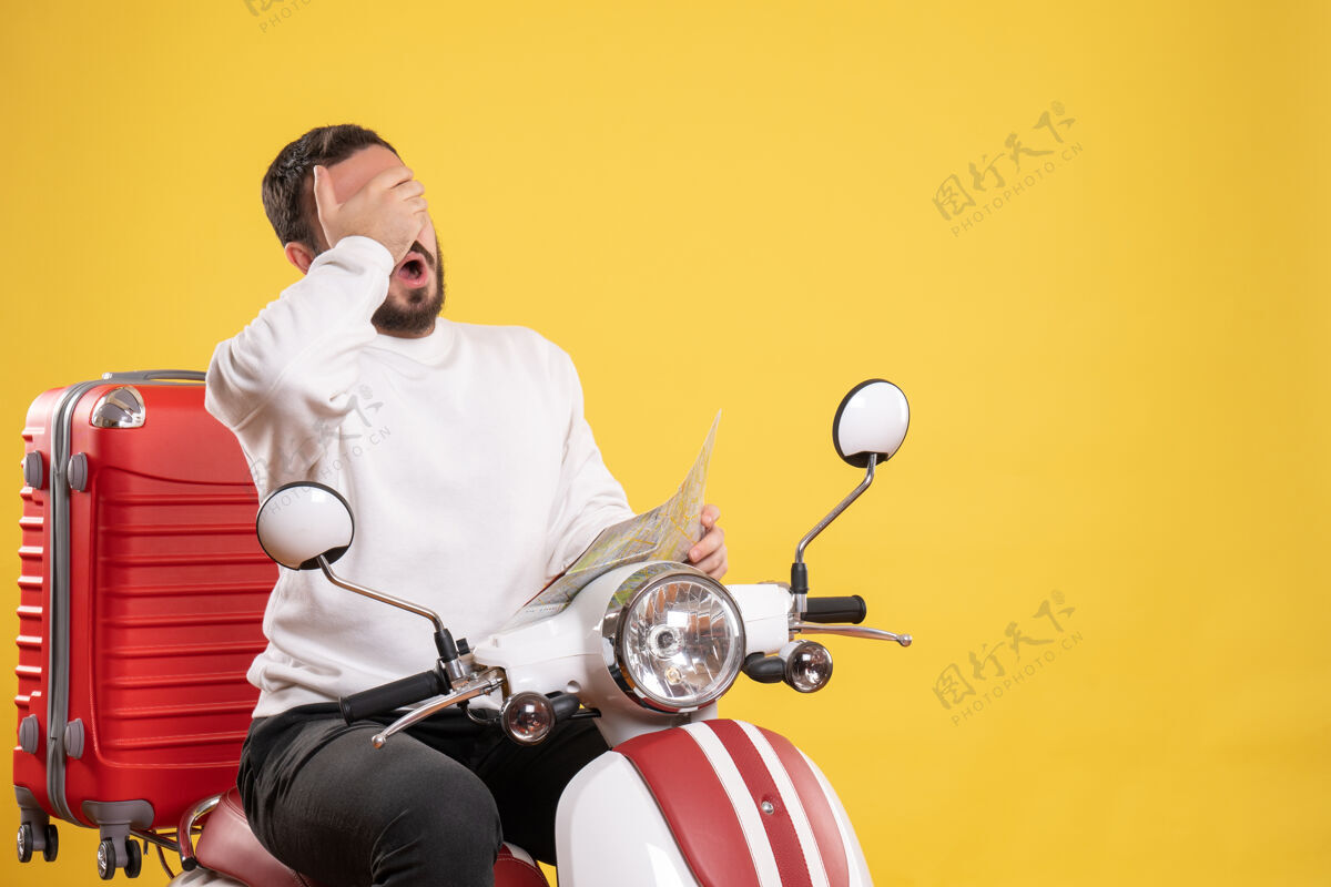 地图旅行概念和疲惫的家伙坐在摩托车上 手提箱上拿着黄色的地图冠军训练车辆