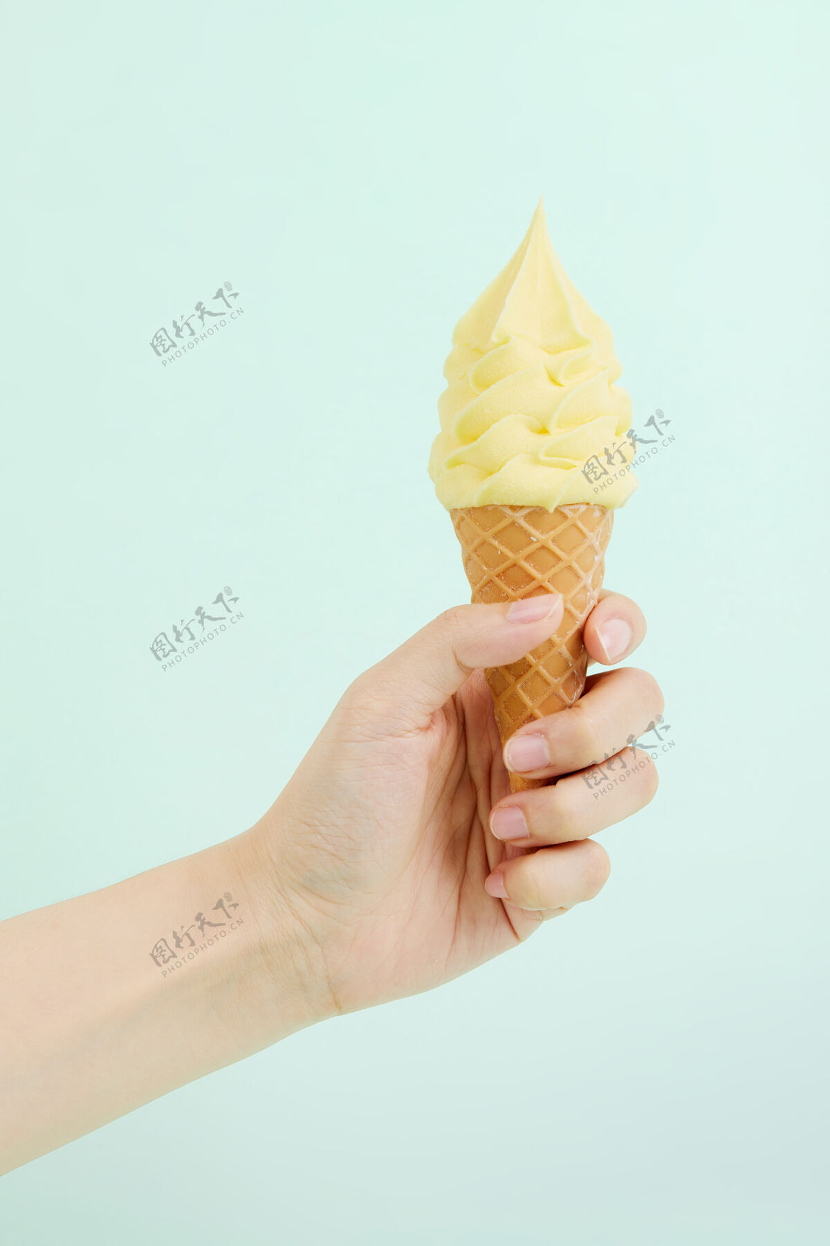 冷的在蓝色的墙上 一只手拿着松脆的华夫饼筒里美味的软冰淇淋美味的夏天甜点