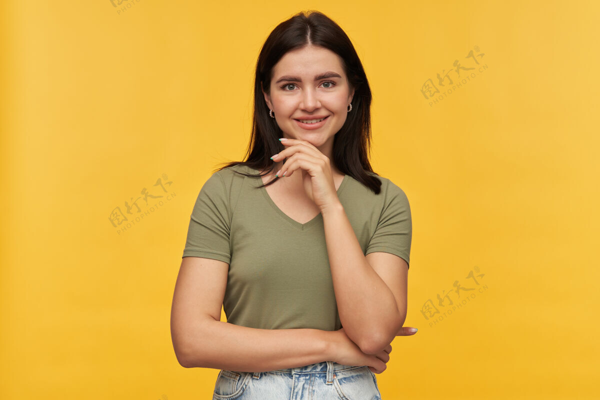 黑发一位身着休闲服的黑发快乐自信的年轻女子的画像 双手交叉在黄色的墙上姿势女性成人