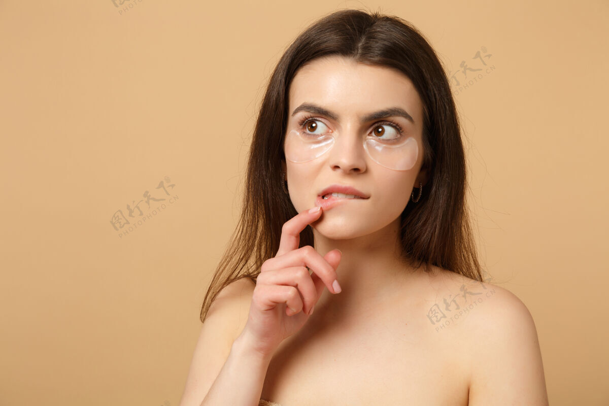 眼睛近距离拍摄完美皮肤的半裸女人 在米色粉彩墙上隔离眼睛下的裸妆贴片清晰治疗塑料