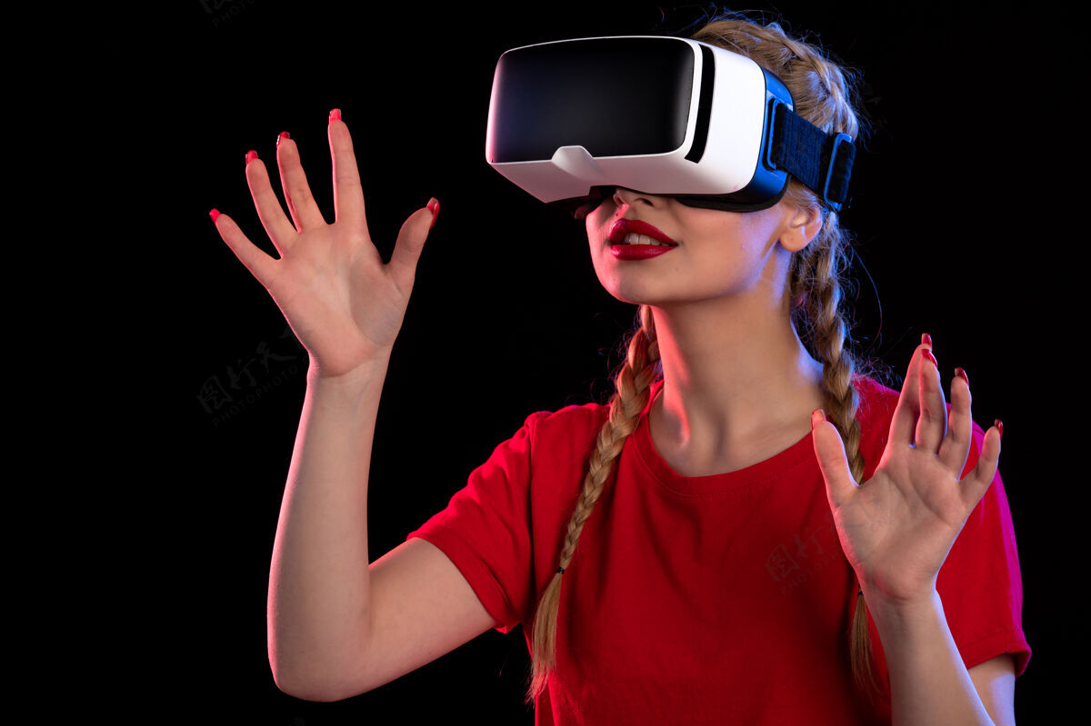 现实年轻女性兴奋地在黑暗的墙上玩虚拟现实的画像年轻女性女士成人