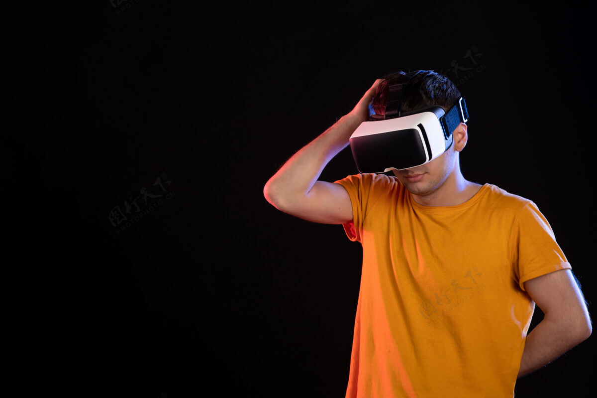 黑暗在黑暗的墙壁上玩虚拟现实的年轻男性的正面视图成人肖像现实