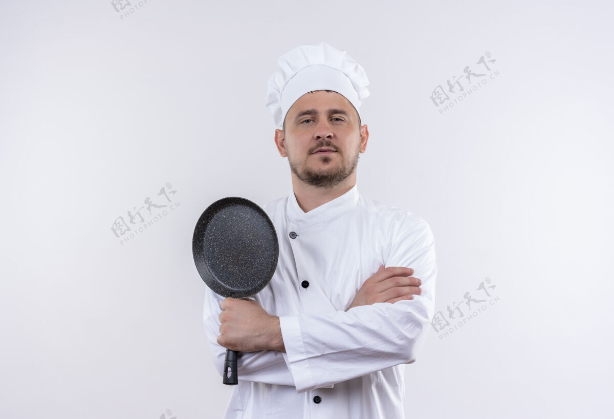 制服自信的年轻帅哥厨师身着厨师制服 站在白色墙壁上 手拿煎锅 姿势封闭厨师烹饪封闭