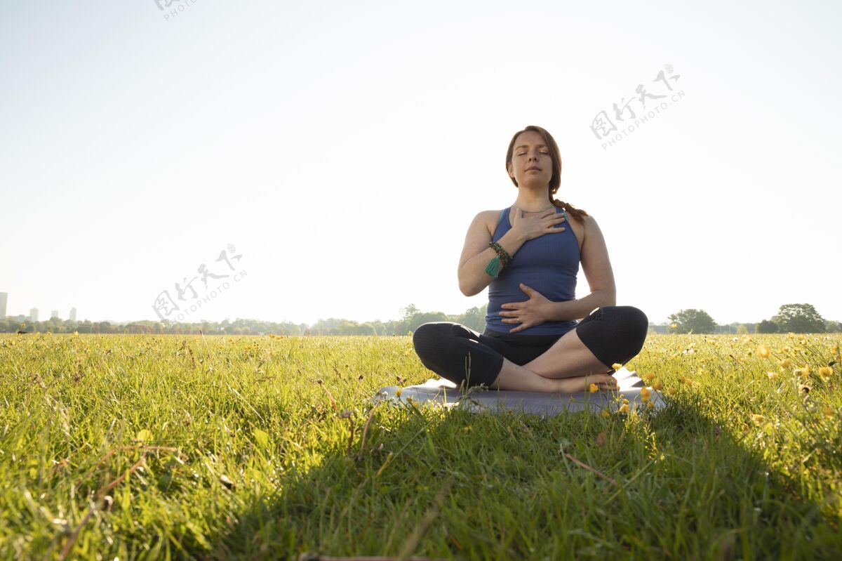 瑜伽年轻女子在户外瑜伽垫上冥想复制空间横向外部