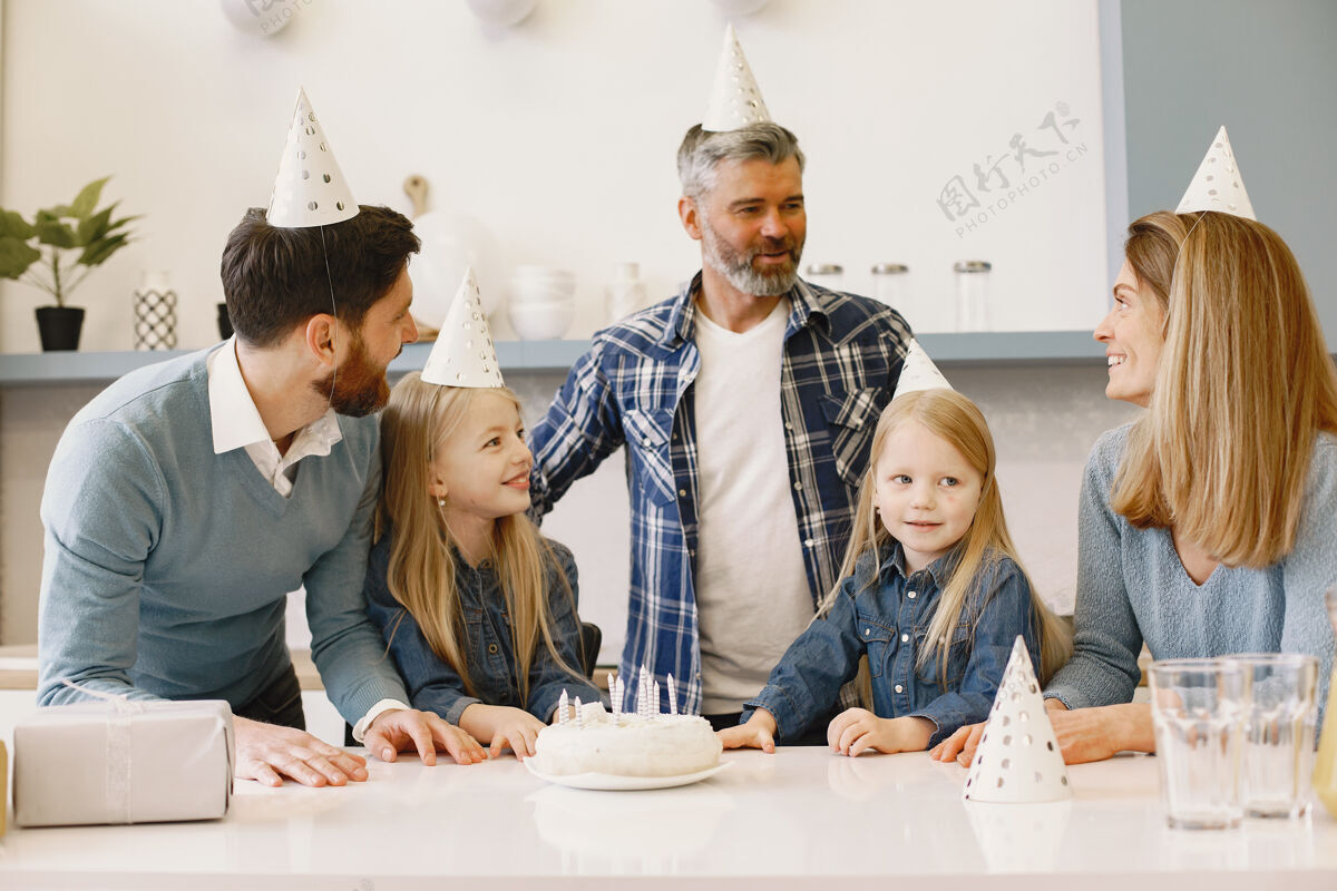 父亲一家人和他们的两个女儿在庆祝桌子上有一个蜡烛蛋糕男人爸爸房子
