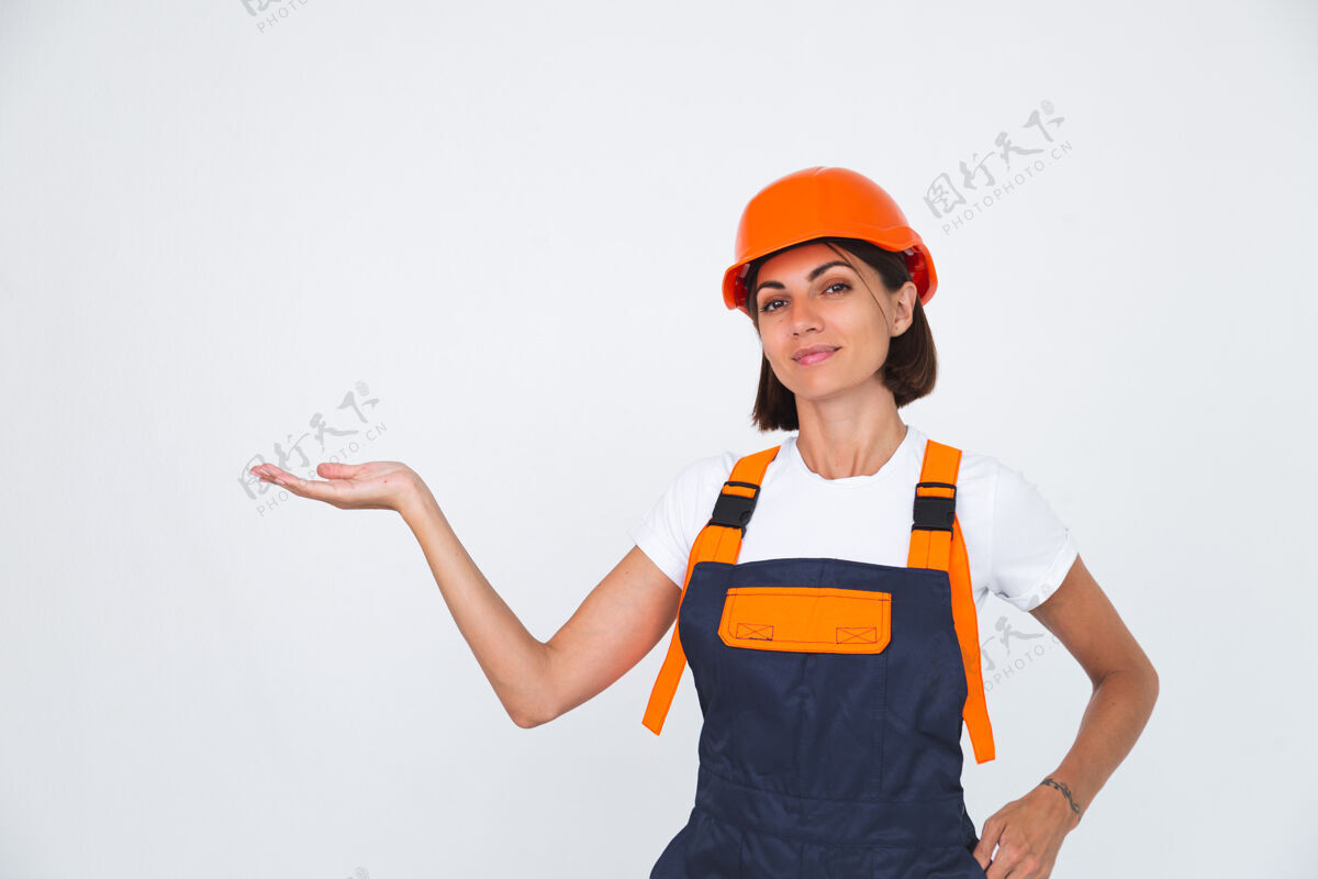 复制空间漂亮的女工程师在建筑物上戴着白色的防护头盔自信地微笑着左手拿着空位建筑女性工程师