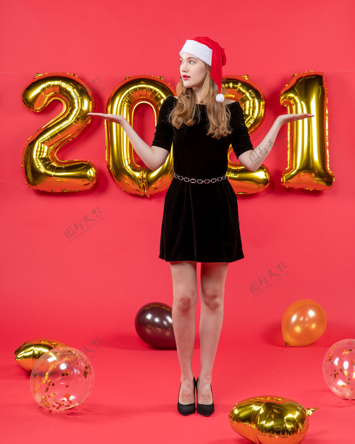 手正面图年轻漂亮的女性穿着黑色连衣裙张开双手气球在红色装置气球黄铜