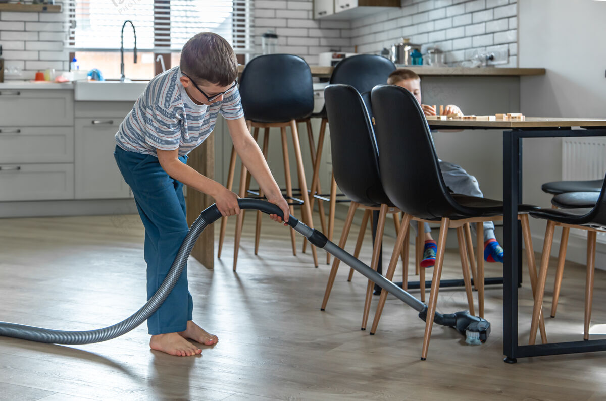 室内一个戴眼镜的小男孩用吸尘器打扫房子人打扫吸尘器