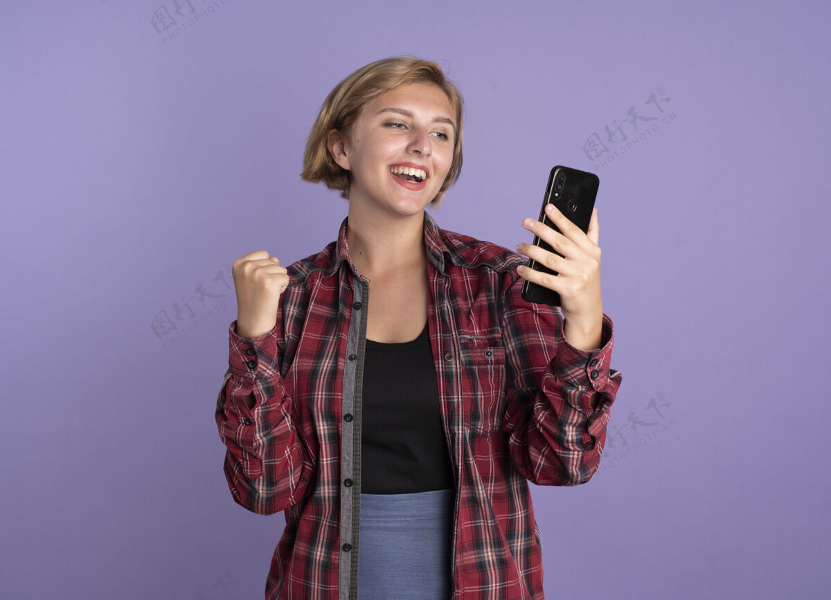 电话快乐的年轻斯拉夫女学生一直握着拳头看电话紫色保持空间
