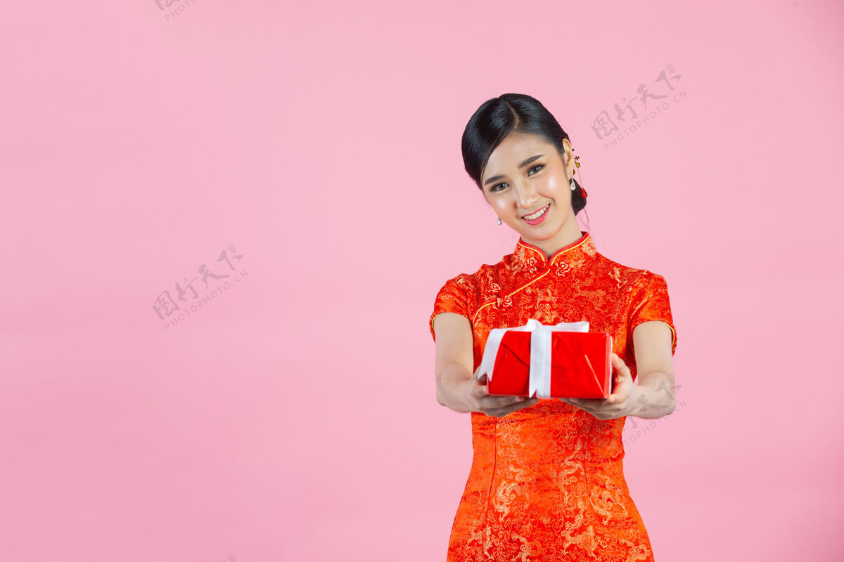 展示美丽的亚洲女人开心的微笑 拿着粉红色背景的中国新年礼盒东方亚洲礼物