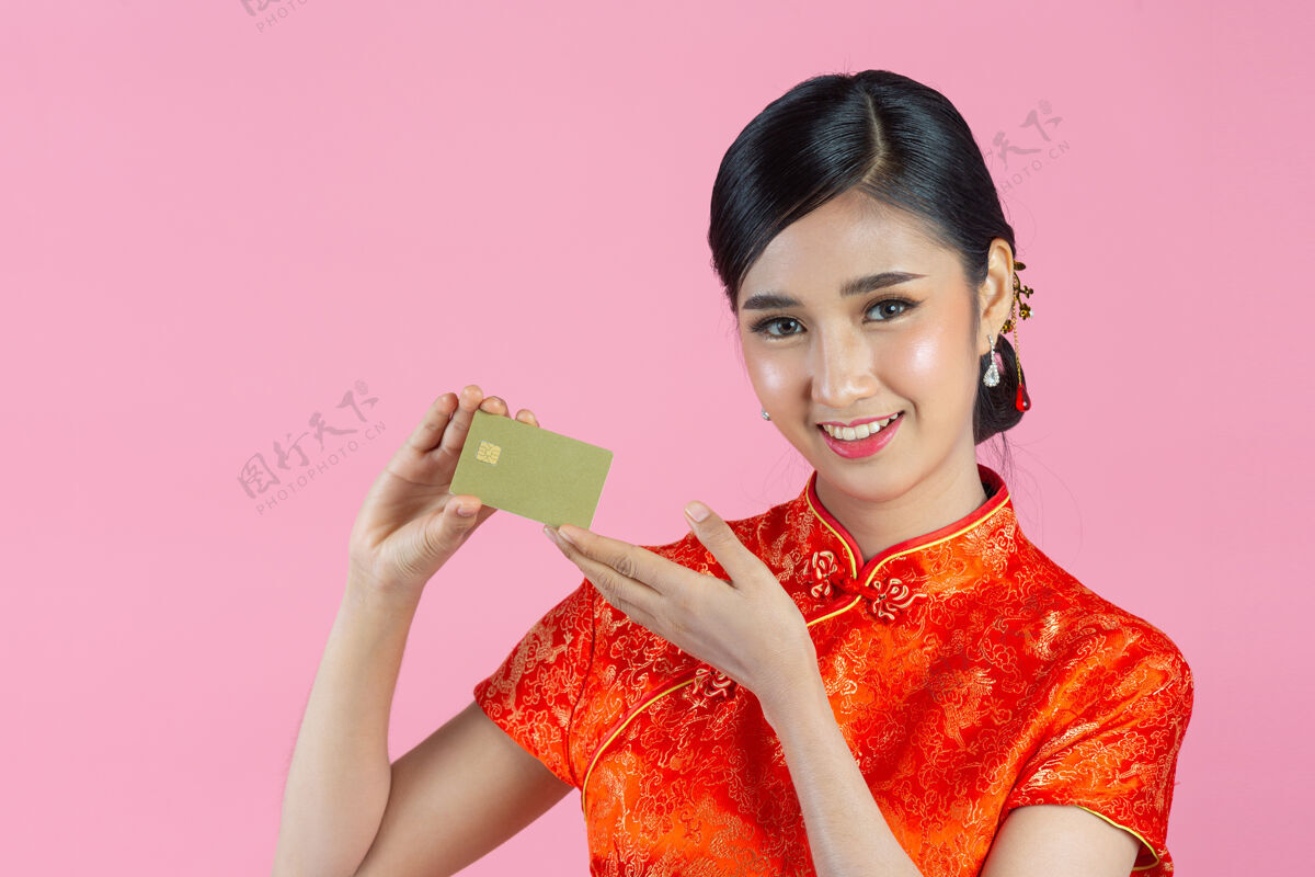 欢呼美丽的亚洲女人开心的微笑 在粉色背景上展示中国新年的信用卡年轻信用卡东方