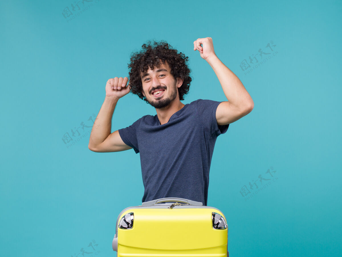 度假带着黄色手提箱度假的男人在蓝色上感到快乐黄旅行人