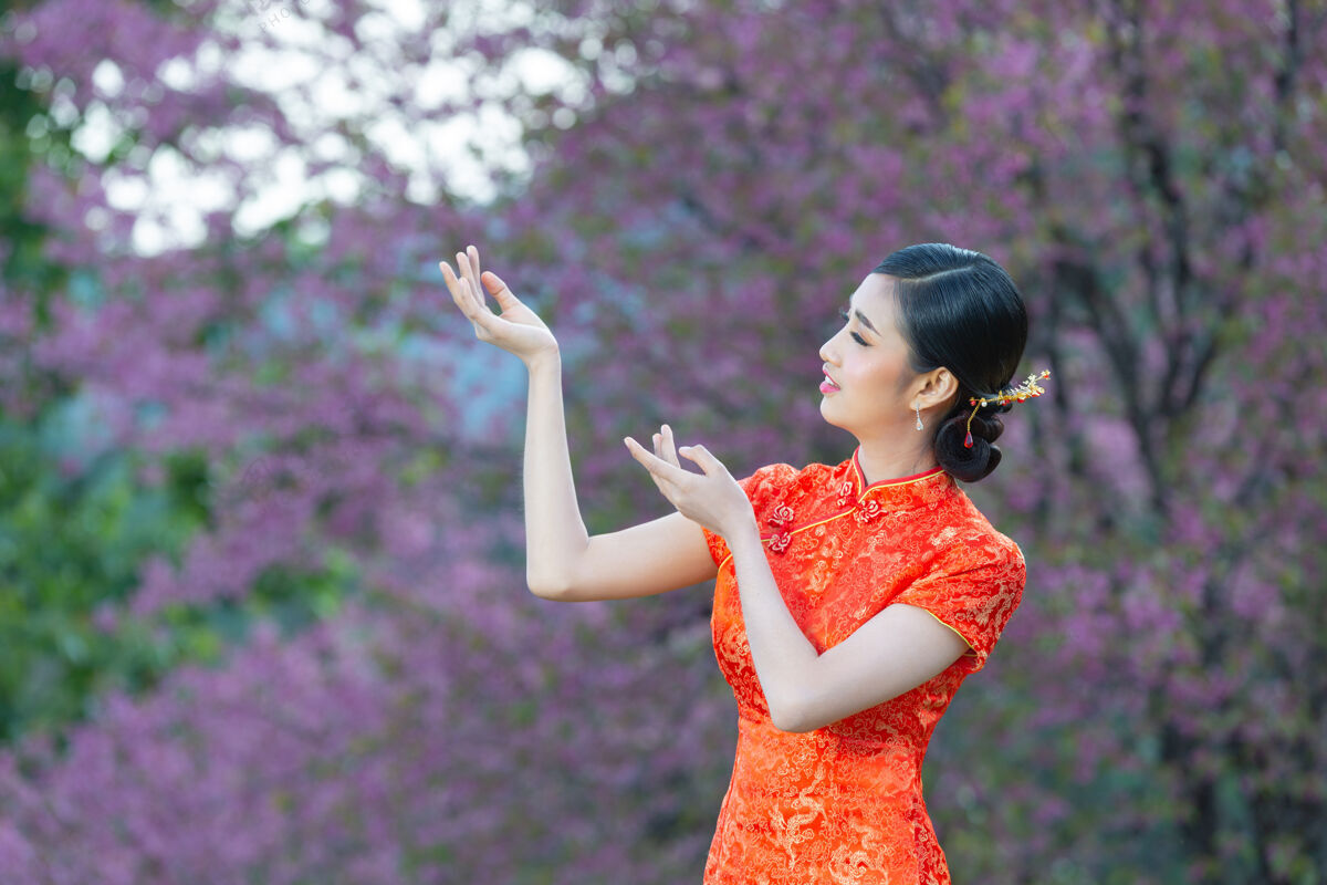 文化美丽的亚洲女人快乐的微笑 在中国新年的粉红色背景上向你展示一些东西微笑新年轻人