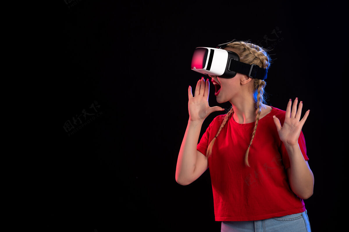 人物年轻女性在黑暗的墙上玩虚拟现实的正面图虚拟现实正面肖像