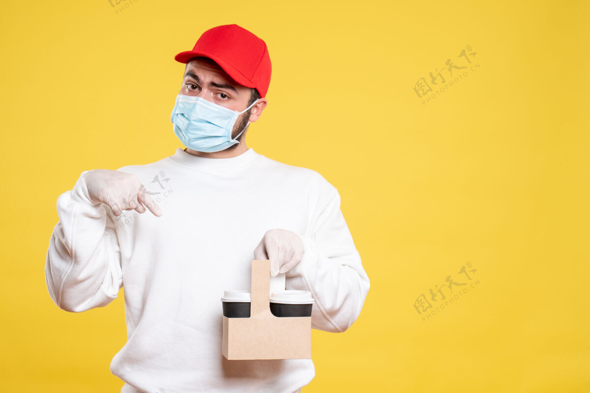 男人戴着面具的男信使拿着黄色的送咖啡送货服务流行病