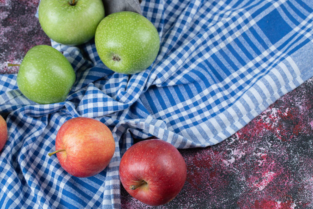 异国情调红色和绿色的苹果被隔离在蓝色格子毛巾上多汁食物可口