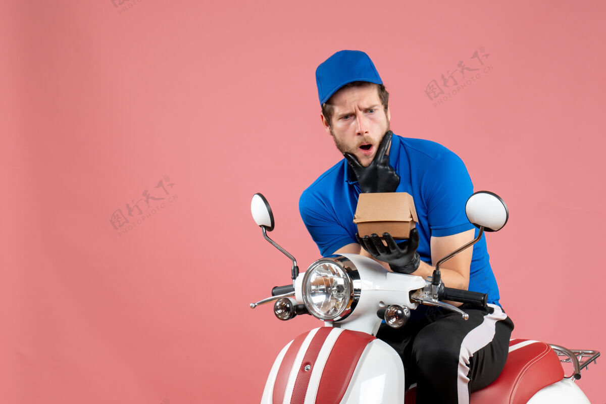 抱着正面图男性信使坐在自行车上 拿着粉红色的小食品包工人服务工作