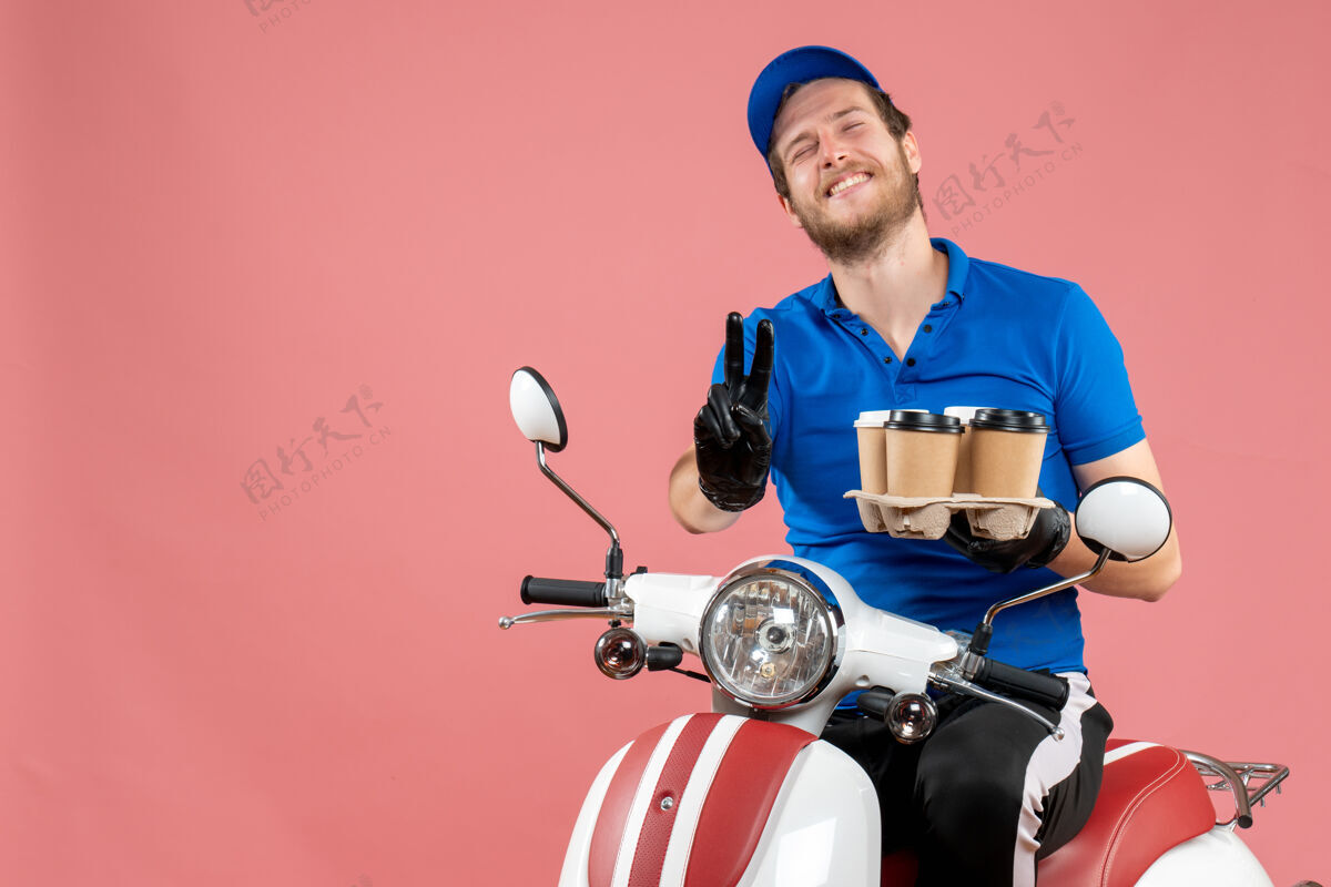 拿着正面图男性信使坐在自行车上拿着咖啡杯的粉红色工作工作制服