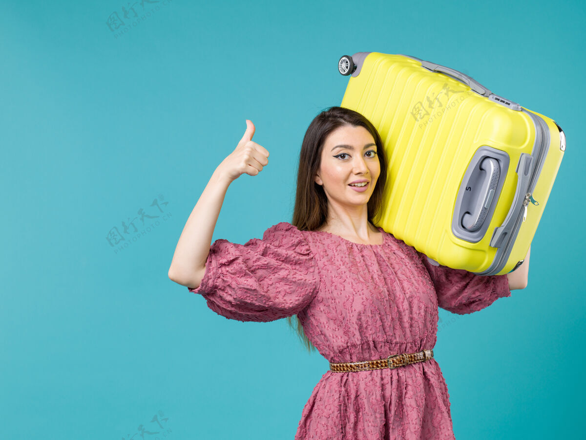 旅程前视图年轻女子带着她的黄色袋子在蓝色背景上度假夏季旅行人类旅行女人海美丽微笑年轻的女人