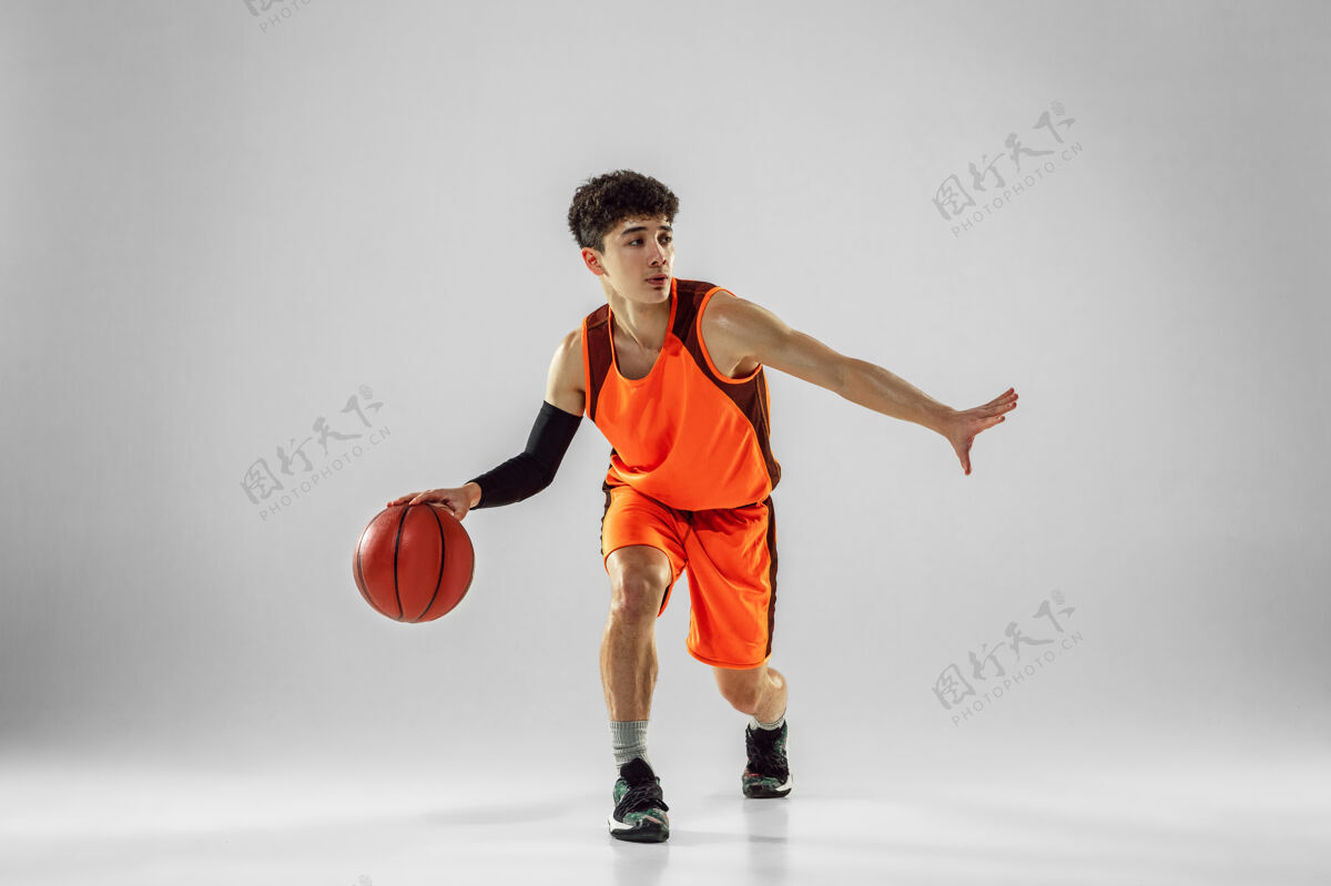 活跃年轻的篮球队员穿着运动服训练 在运动中练习 在运动中奔跑隔离在白墙上大满贯健身房比赛