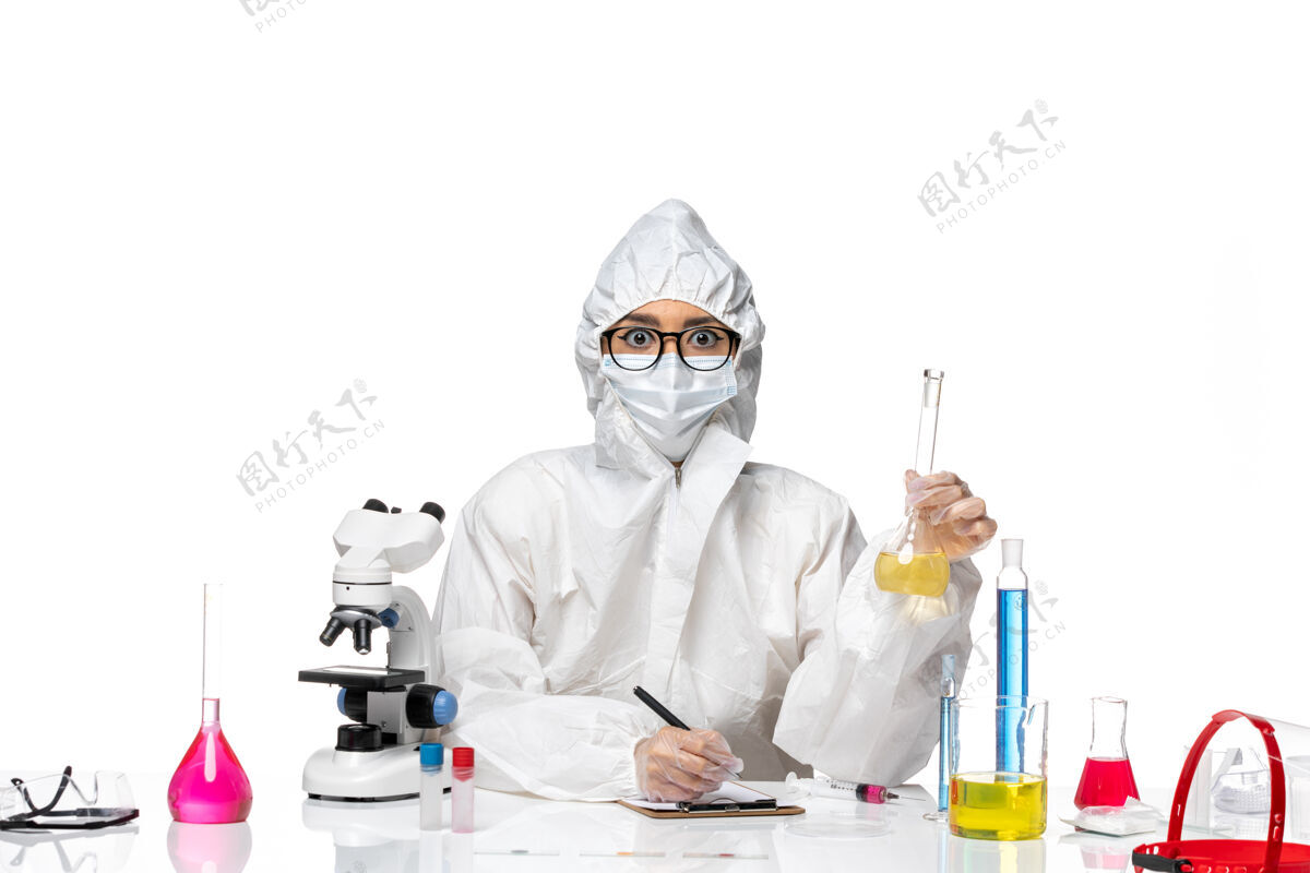 化学正面图身穿特殊防护服的年轻女化学家拿着装有溶液的烧瓶 在白色背景上写着实验室的冠状病毒化学病毒面具病毒实验室外套