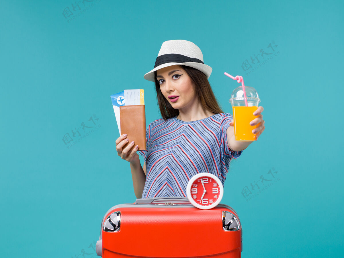 微笑前景度假中的女人拿着机票和果汁在蓝色的背景上航行度假之旅女海帽子人旅行