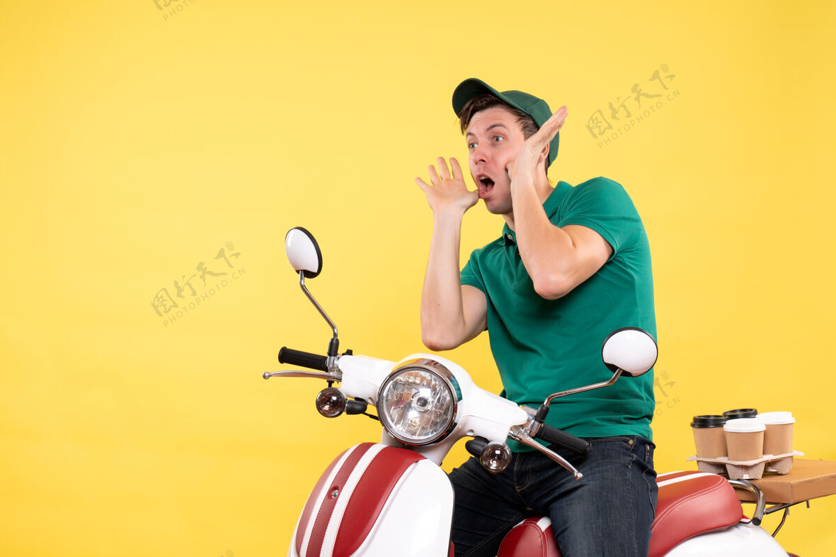 年轻男性信使正面图：身穿黄色绿色制服的年轻男性信使摩托车工人车辆