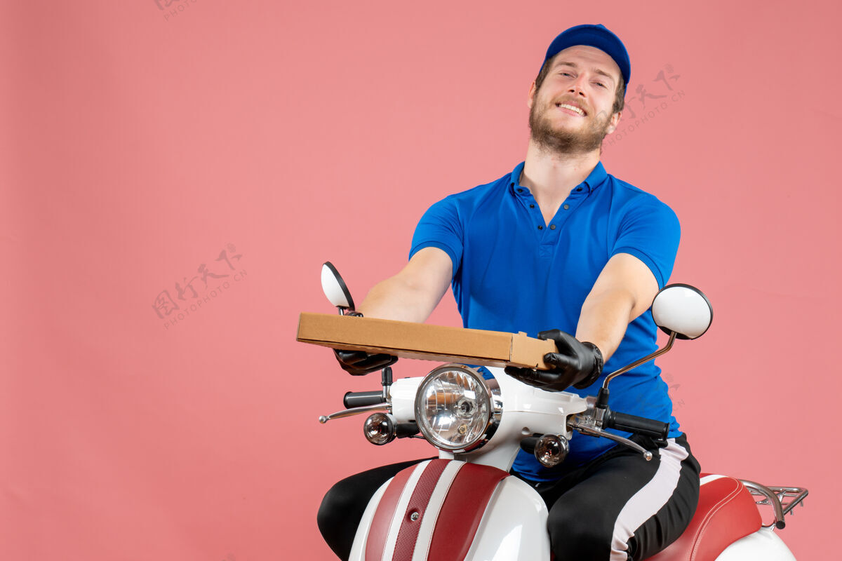 工人正面图男性信使坐在自行车上 拿着粉红色的比萨饼盒快餐比萨饼送货