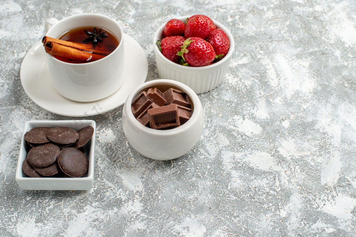 早餐在灰白色背景的左上角有草莓 巧克力和肉桂茴香籽茶的底视图碗杯子早晨底部
