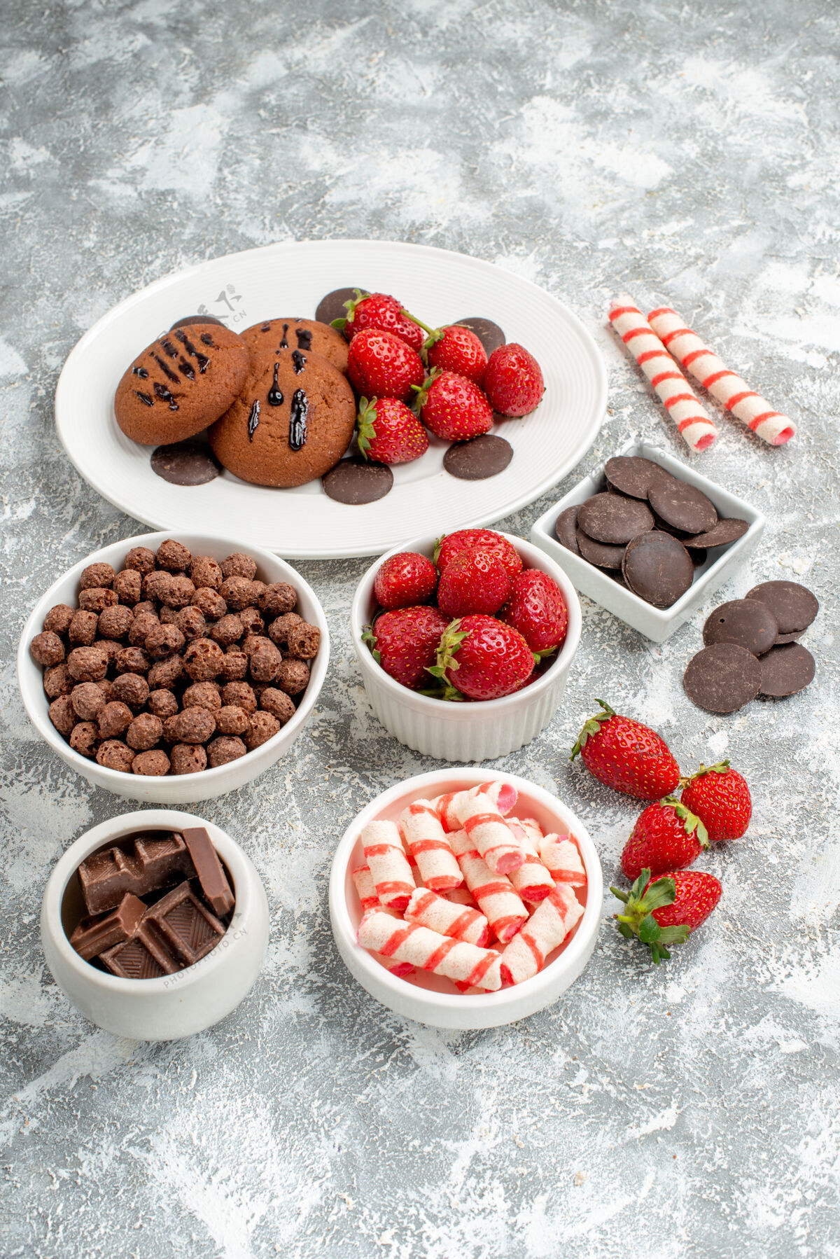 草莓底视图饼干草莓和圆形巧克力放在白色椭圆形盘子碗里 糖果草莓巧克力麦片放在灰白色的桌子上巧克力可食用水果餐桌